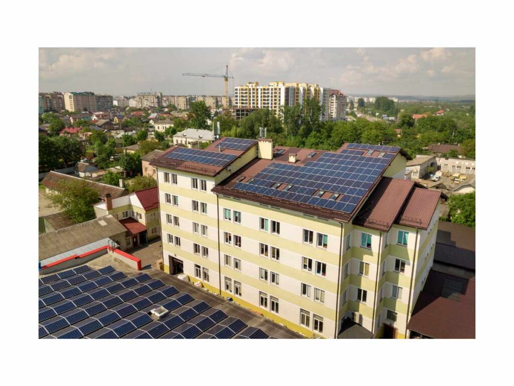 Widok z lotu ptaka na budynek wielorodzinny z dużą instalacją paneli fotowoltaicznych na dachu